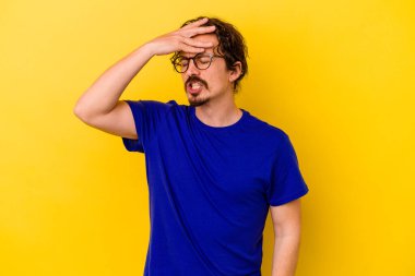 Sarı arka planda izole edilmiş genç beyaz adam tapınaklara dokunuyor ve baş ağrısı çekiyor..