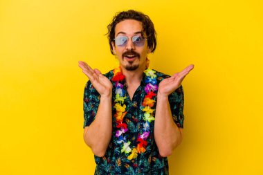 Sarı arka planda izole edilmiş Hawaii kolyesi takan genç beyaz adam şaşırdı ve şok oldu..