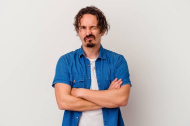 Beyaz arka planda izole edilmiş genç beyaz adam alaycı bir ifadeyle kameraya bakıyor..