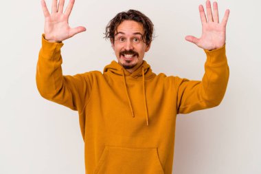 Beyaz arka planda izole olmuş genç beyaz bir adam zaferi veya başarıyı kutluyor, şaşırıyor ve şok oluyor..