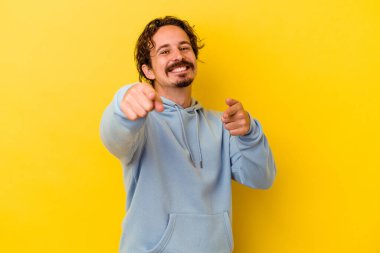 Sarı arka planda izole edilmiş genç beyaz adam öne bakan neşeli gülücükler.