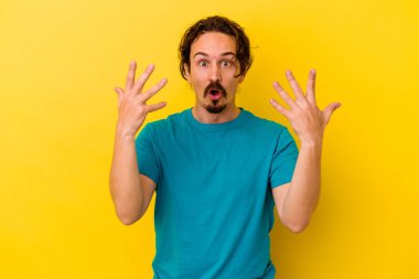 Sarı arka planda izole edilmiş genç beyaz adam on numarayı elleriyle gösteriyor..