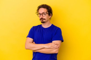 Sarı arka planda izole edilmiş genç beyaz adam alaycı bir ifadeyle kameraya bakıyor..