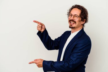 Beyaz arka planda izole edilmiş genç bir iş adamı İşaret parmaklarıyla işaret ederek heyecanlı.