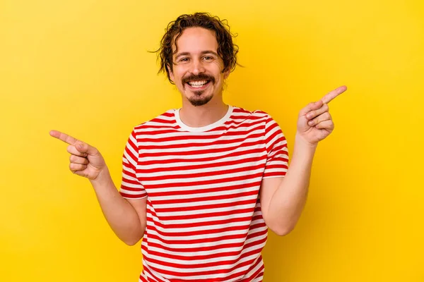 Joven Hombre Caucásico Aislado Sobre Fondo Amarillo Apuntando Diferentes Espacios — Foto de Stock