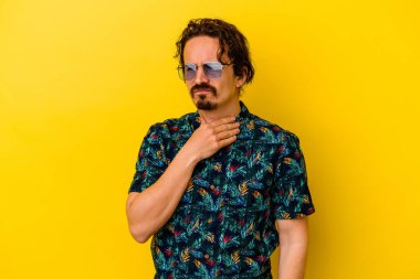 Sarı arka planda izole edilmiş yaz kıyafetleri giyen genç beyaz adam virüs veya enfeksiyon yüzünden boğazında ağrı hissediyor..