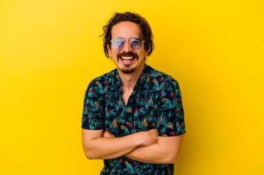 Sarı arka planda izole edilmiş yaz kıyafetleri giyen genç beyaz adam gülüyor ve eğleniyor..