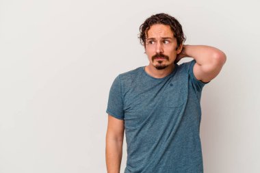 Beyaz arka planda izole edilmiş genç beyaz bir adam kafasının arkasına dokunuyor, düşünüyor ve bir seçim yapıyor..