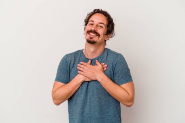Beyaz arka planda izole edilmiş beyaz tenli genç bir adam, dostane bir ifadeye sahip, avuçlarını göğsüne bastırıyor. Aşk konsepti.