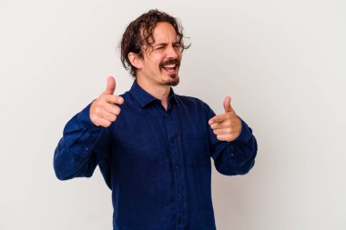 Beyaz arka planda izole edilmiş genç beyaz adam parmaklarıyla ön tarafı işaret ediyor..