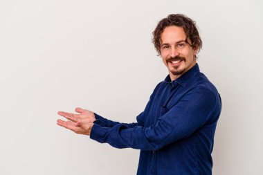 Beyaz arka planda izole edilmiş beyaz tenli genç bir adam palmiyesinde bir kopya alanı tutuyor..