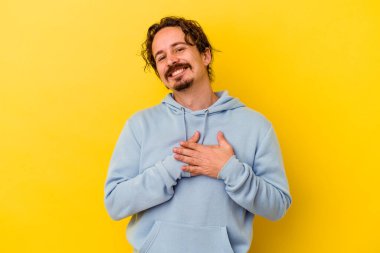 Sarı arka planda izole edilmiş beyaz bir genç, dost canlısı bir ifadeye sahip, avuçlarını göğsüne bastırıyor. Aşk konsepti.