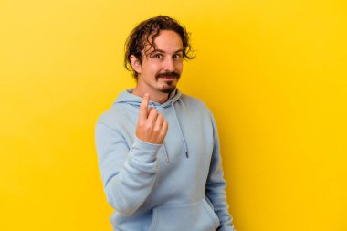 Sarı arka planda izole edilmiş genç beyaz adam sanki seni davet ediyormuş gibi seni işaret ediyor..