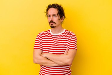 Genç beyaz adam sarı arka planda izole edilmiş şüpheli, belirsiz, seni muayene ediyor..