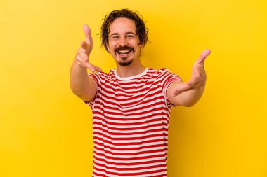 Sarı arka planda izole edilmiş genç beyaz adam kameraya sarıldığı için kendinden emin hissediyor..