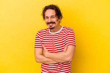 Sarı arka planda izole genç beyaz adam gülüyor ve eğleniyor..