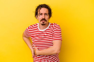 Sarı arka planda karaciğer ağrısı çeken, karnı ağrıyan genç beyaz bir adam..