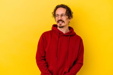 Sarı arka planda izole edilmiş genç beyaz adam gülümseyen, neşeli ve keyifli görünüyor..