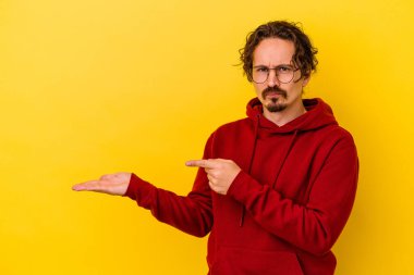 Sarı arka planda izole edilmiş genç beyaz bir adam, elinde bir fotokopi alanı tutarken heyecanlanıyor..