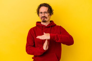 Sarı arka planda izole edilmiş genç beyaz adam bir mola hareketi gösteriyor..