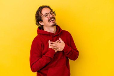 Sarı arka planda izole edilmiş beyaz bir genç, dost canlısı bir ifadeye sahip, avuçlarını göğsüne bastırıyor. Aşk konsepti.