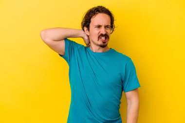 Sarı arka planda izole edilmiş genç beyaz adam yorgun ve uykulu bir şekilde ellerini başının üstünde tutuyor..