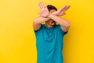 Sarı arka planda izole genç beyaz adam iki kolu çapraz tutuyor, inkar kavramı.