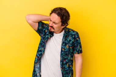 Sarı arka planda izole edilmiş genç beyaz bir adam stresten dolayı boynu ağrıyor, masaj yapıyor ve elle dokunuyor..