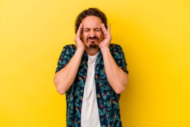 Sarı arka planda izole edilmiş genç beyaz adam tapınaklara dokunuyor ve baş ağrısı çekiyor..