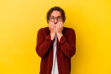 Sarı arka planda izole edilmiş, tırnak yiyen, gergin ve endişeli genç bir beyaz adam..