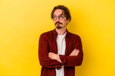 Sarı arka planda izole edilmiş genç beyaz adam hedeflere ve amaçlara ulaşma hayali kuruyor.