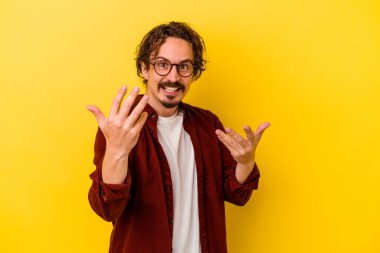 Sarı arka planda izole edilmiş genç beyaz adam sanki seni davet ediyormuş gibi seni işaret ediyor..