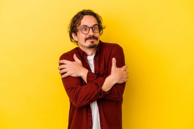 Sarı arka plan kucaklamalarında izole edilmiş genç beyaz adam, kaygısız ve mutlu gülümsüyor..