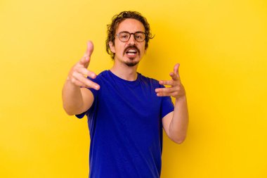 Sarı arka planda izole edilmiş genç beyaz adam kameraya sarıldığı için kendinden emin hissediyor..