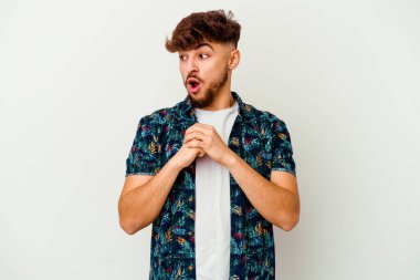 Faslı genç bir adam beyaz arka planda izole edilmiş şans diliyor, şaşırmış ve ağzını açıp önüne bakıyor..