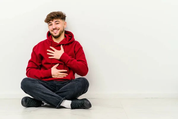 Giovane Marocchino Seduto Sul Pavimento Isolato Sfondo Bianco Ride Felicemente — Foto Stock