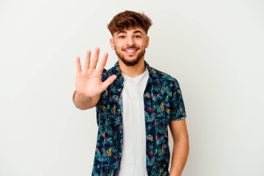 Genç Faslı adam beyaz arka planda izole edilmiş. Gülümsüyor. Beş numarayı parmaklarıyla gösteriyor..