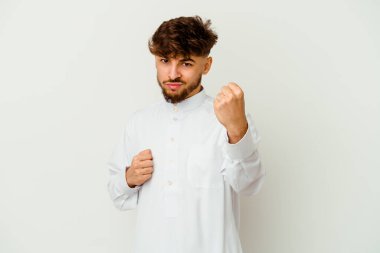 Beyaz arka planda izole edilmiş tipik Arap kıyafetleri giyen genç Faslı adam kameraya yumruk gösteriyor, agresif yüz ifadesi var..