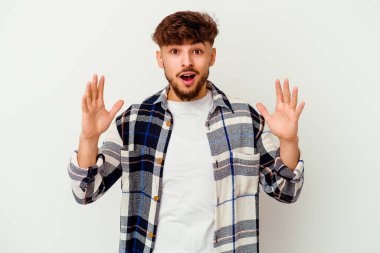 Faslı genç bir adam beyaz arka planda izole edilmiş. Hoş bir sürpriz bekliyor. Heyecanlı ve el kaldırıyor..