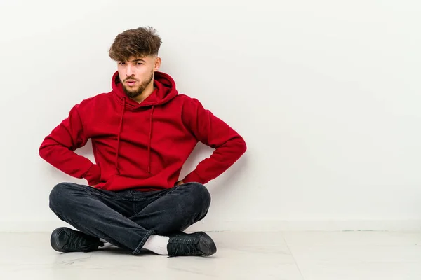 Jovem Marroquino Sentado Chão Isolado Fundo Branco Sopra Bochechas Tem — Fotografia de Stock