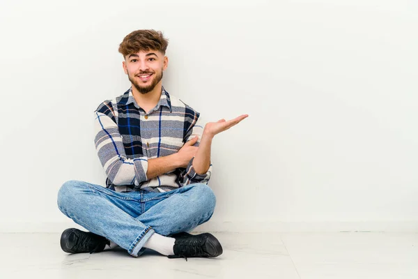 Jonge Marokkaanse Man Zit Vloer Geïsoleerd Witte Achtergrond Toont Een — Stockfoto