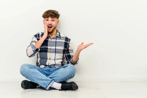 Young Moroccan Man Sitting Floor Isolated White Background Impressed Holding — Stock Photo, Image