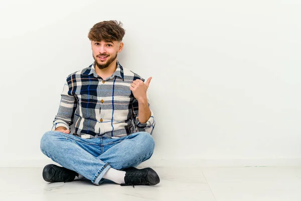 Νεαρός Μαροκινός Κάθεται Στο Πάτωμα Απομονωμένος Λευκό Φόντο Σοκαρισμένος Δείχνοντας — Φωτογραφία Αρχείου