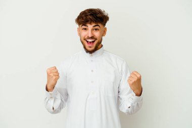 Beyaz arka planda izole edilmiş tipik bir Arap kıyafeti giyen genç Faslı adam tasasız ve heyecanlı tezahüratlar yapıyor. Zafer konsepti.