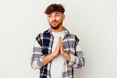 Faslı genç bir adam beyaz arka planda izole edilmiş dua ediyor, bağlılık gösteriyor, dindar biri ilahi ilham arıyor..