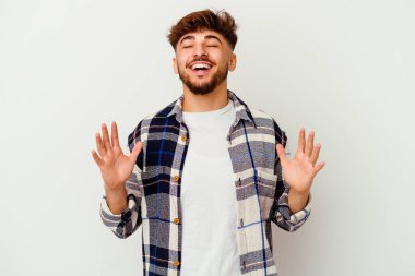 Beyaz arka planda yaşayan genç Faslı adam elini göğsüne koyduğunda kahkahalar atıyor..