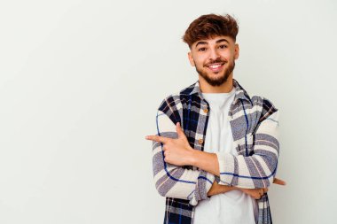 Beyaz arka planda izole edilmiş genç Faslı adam işaret parmağıyla işaret ederek gülümsüyor..