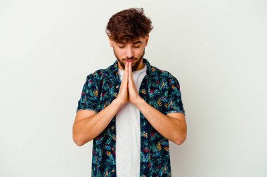 Faslı genç bir adam beyaz arka planda izole edilmiş dua ediyor, bağlılık gösteriyor, dindar biri ilahi ilham arıyor..