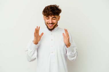 Beyaz arka planda izole edilmiş tipik bir Arap kıyafeti giyen genç Faslı adam çok gülüyor. Mutluluk kavramı.