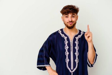 Faslı genç bir adam beyaz arka planda izole edilmiş. Parmağıyla bir numarayı gösteriyor..
